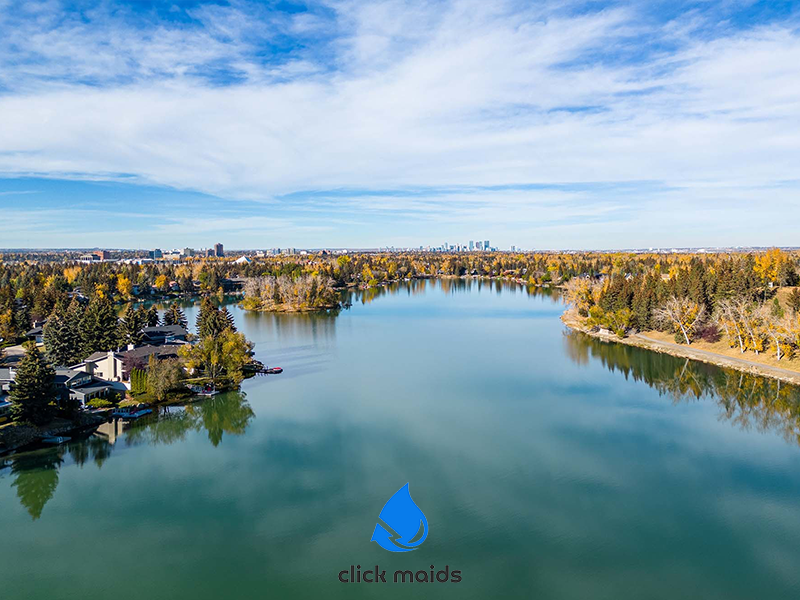 Aerial view of Lake Bonavista, Calgary, in autumn, with residential homes and the city skyline.