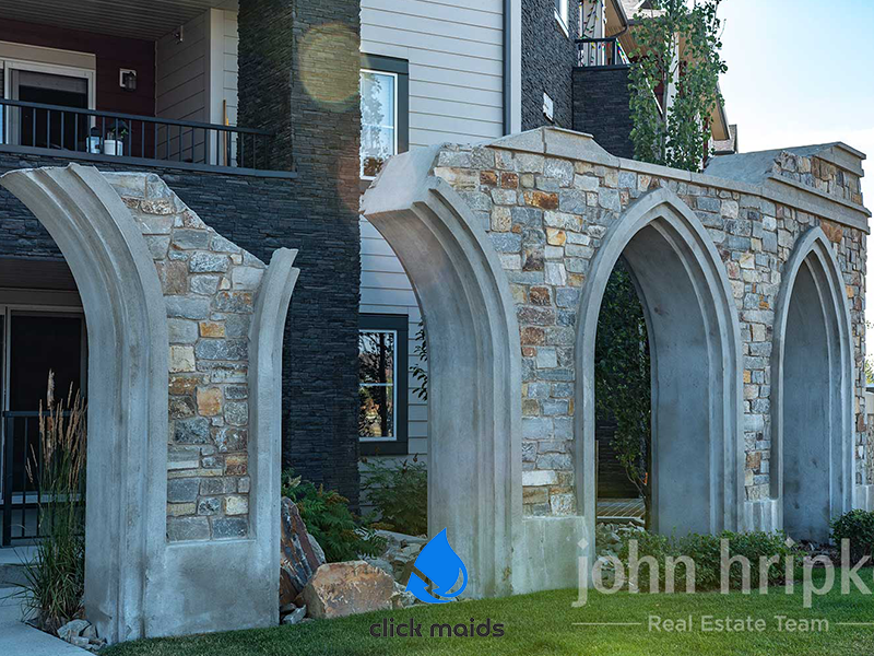 Gothic stone archway landmark in Legacy, Calgary, with modern residential buildings behind.