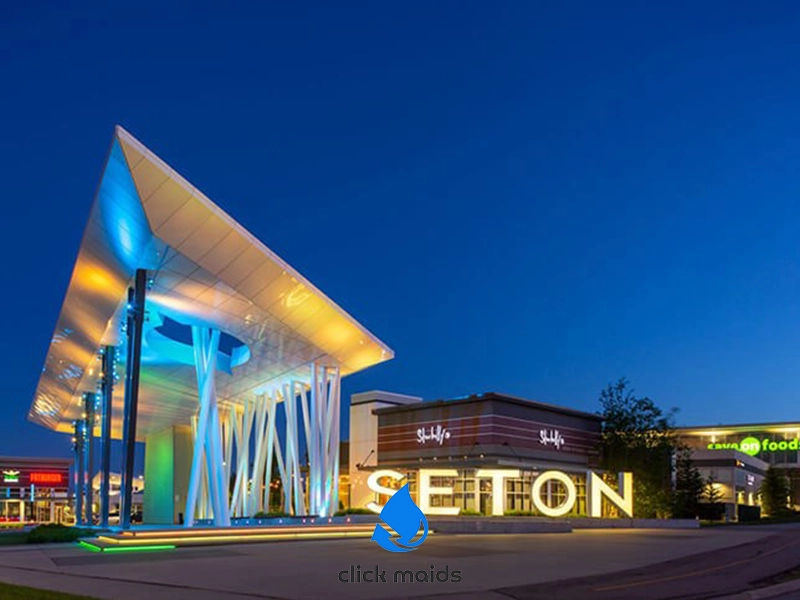 "Illuminated SETON canopy with angular beams and retail signs at twilight, including Shoppers Drug Mart and Save-On-Foods, 'click maids' logo below."