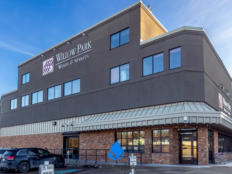 "Modern building with Willow Park Wines & Spirits signage, brick and metal siding, ramp entrance, parked cars, and 'click maids' logo below."
