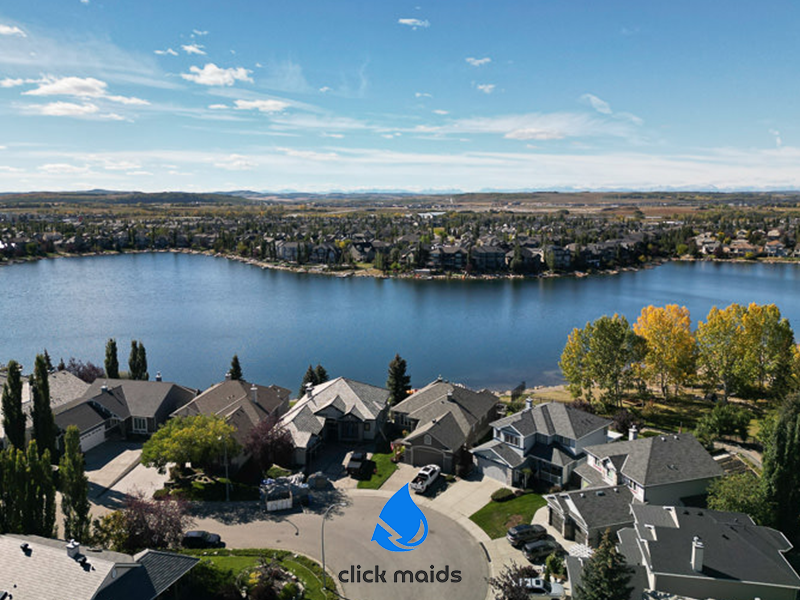 Aerial view of Chaparral, Calgary homes on a cul-de-sac overlooking a large blue lake on a sunny day.