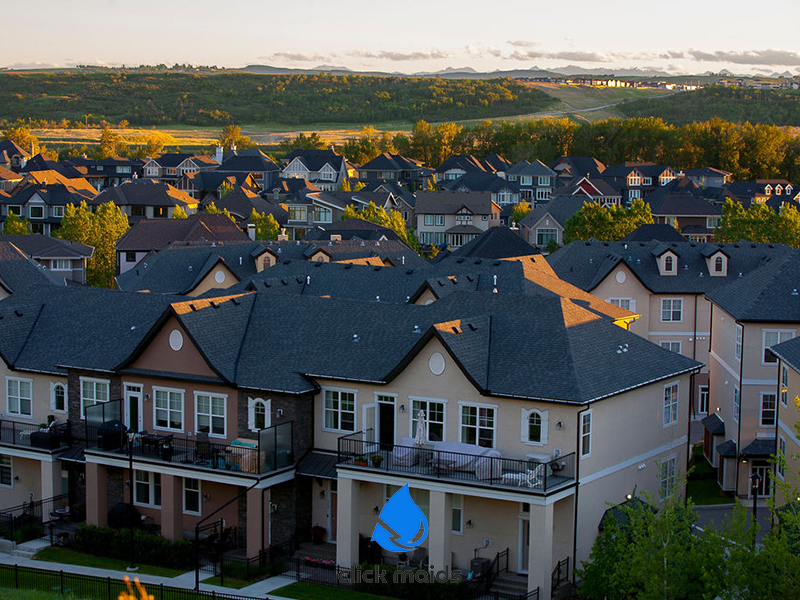 Townhouses and houses in Cranston, Calgary, bathed in golden evening light with foothills background.