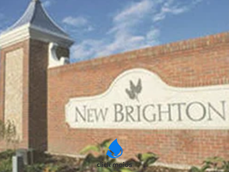 Brick entrance wall and sign for New Brighton community under a bright blue sky.