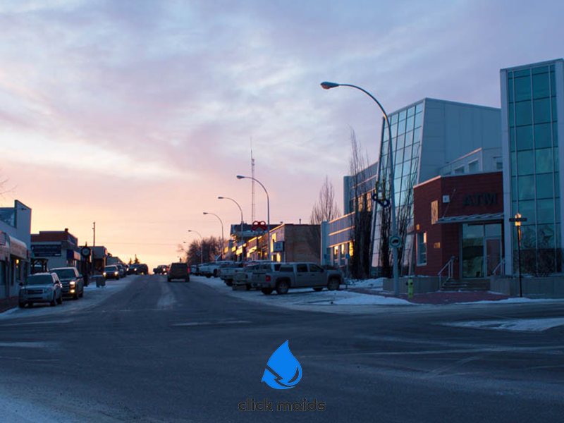 Winter sunrise over a quiet downtown street in Olds Alberta with parked trucks and modern glass buildings