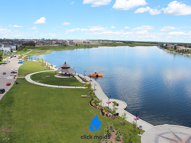 Peaceful lakeside park in Airdrie Alberta with walking paths, open green space, and a small pavilion by the water